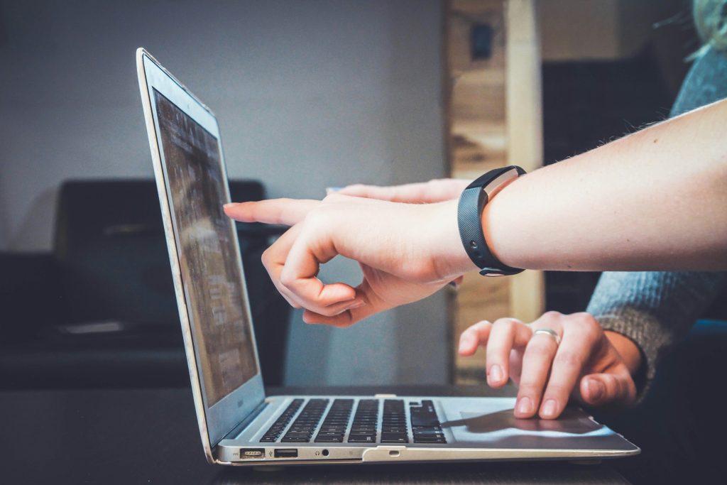 persoon wijst naar laptop scherm.